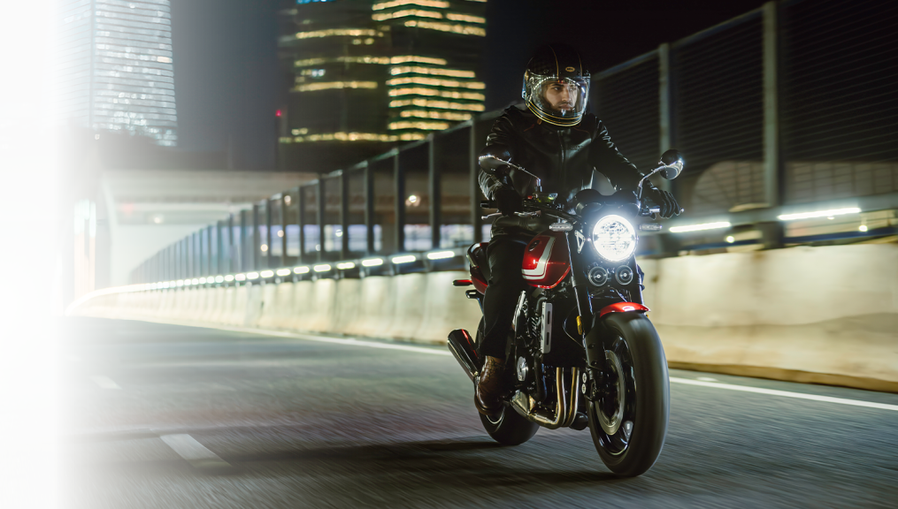 ZXMOTO 500F | Night Riding Feature A rider on a red 500F with a bright round headlight travels through a city at night, with a pale fade at the left.