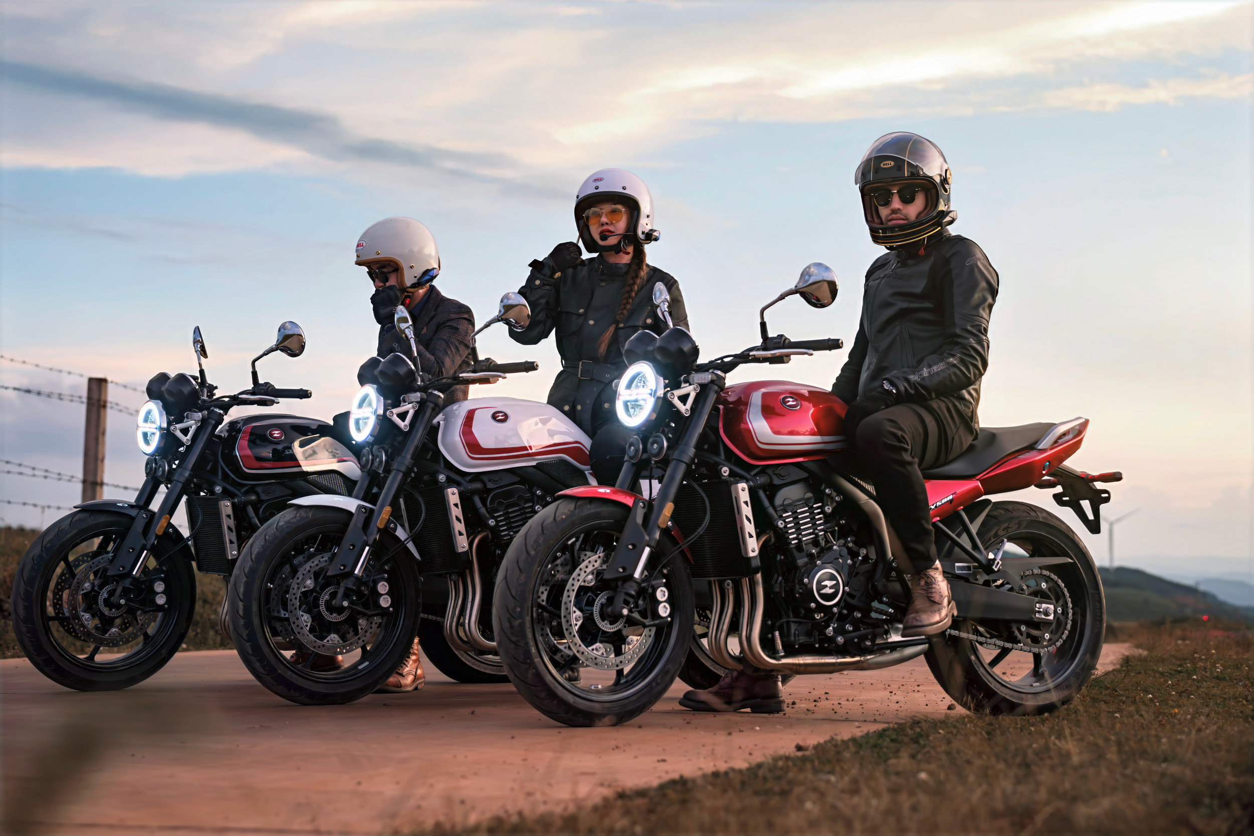 ZXMOTO 500F | Riders at a Scenic Overlook Three helmeted riders on motorcycles with round headlights line up at a dirt overlook under an evening sky.