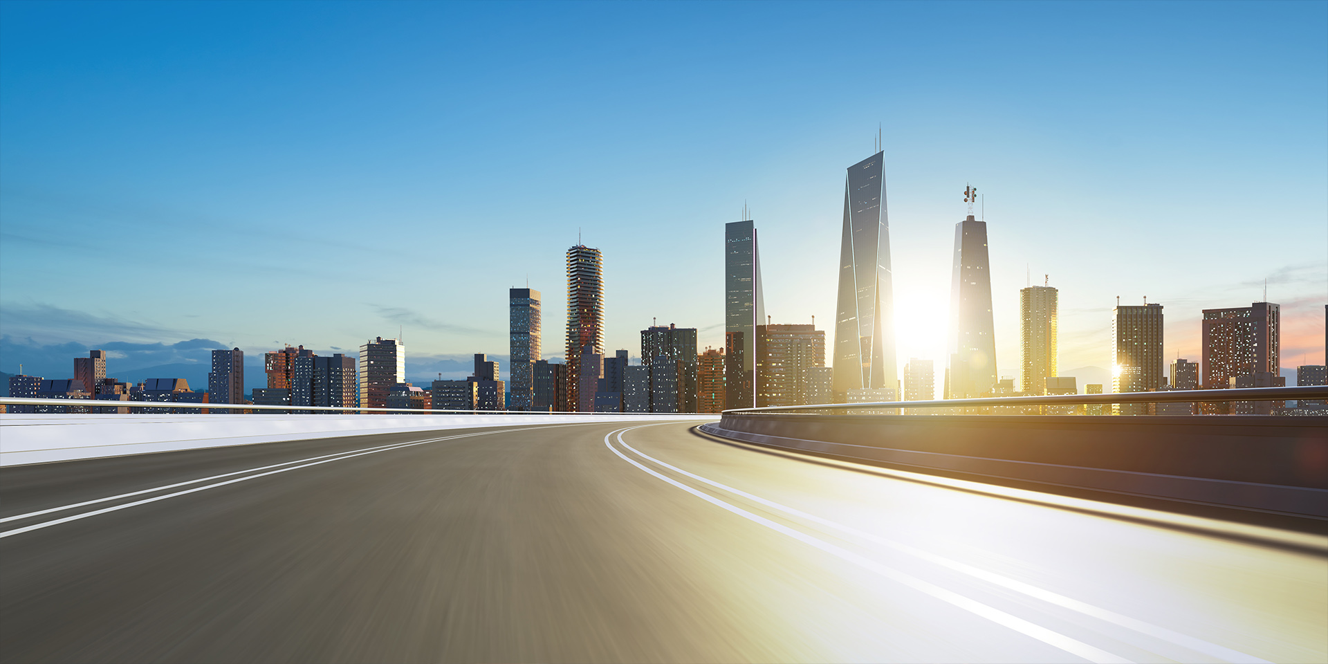 City Skyline and Open Road | 500F Hero Background An empty elevated road curves towards a city skyline with sunlight shining between tall buildings.